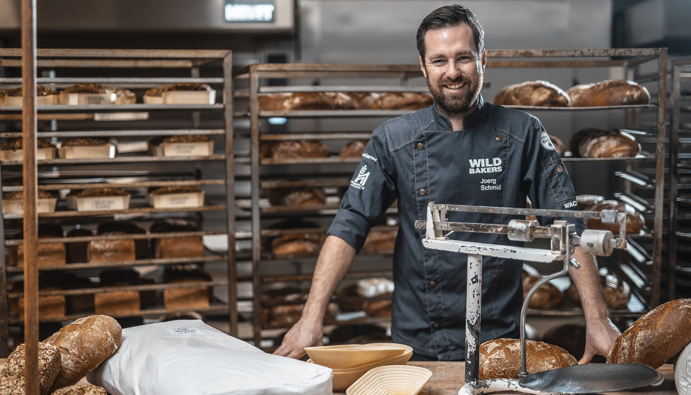 Joerg Schmid, Bäcker der Wild Bakers, steht in seiner Backstube mit frischem Brot.