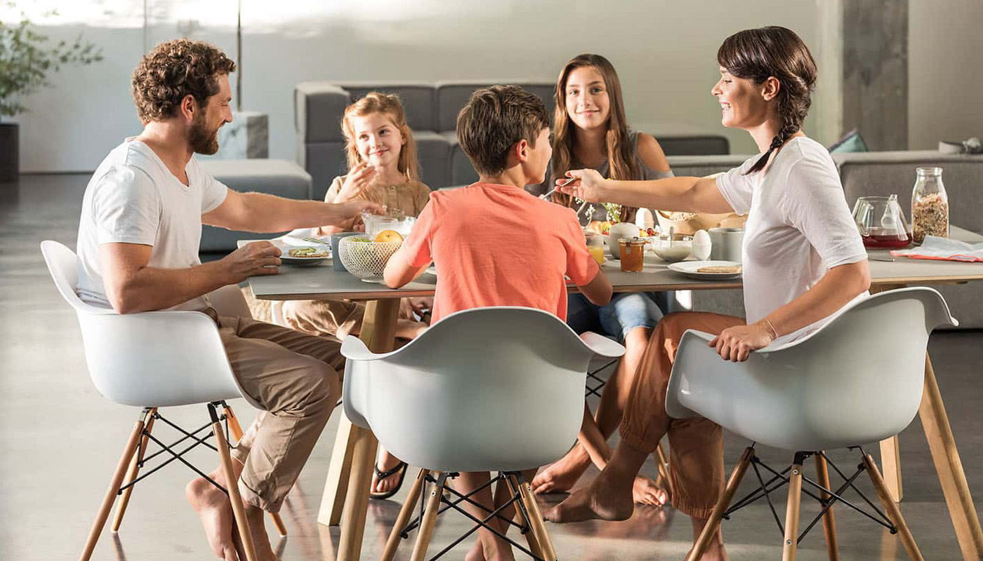 Familie sitzt gemeinsam am Esstisch und genießt ein Frühstück von Morgengold Frühstücksdienste.