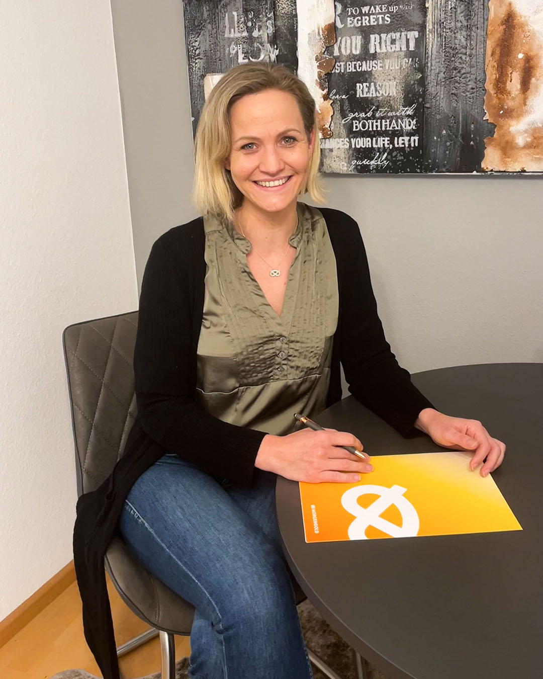 Theresia Tessmer von Morgengold sitzt an einem Tisch und unterschreibt ein Dokument mit Morgengold-Logo.