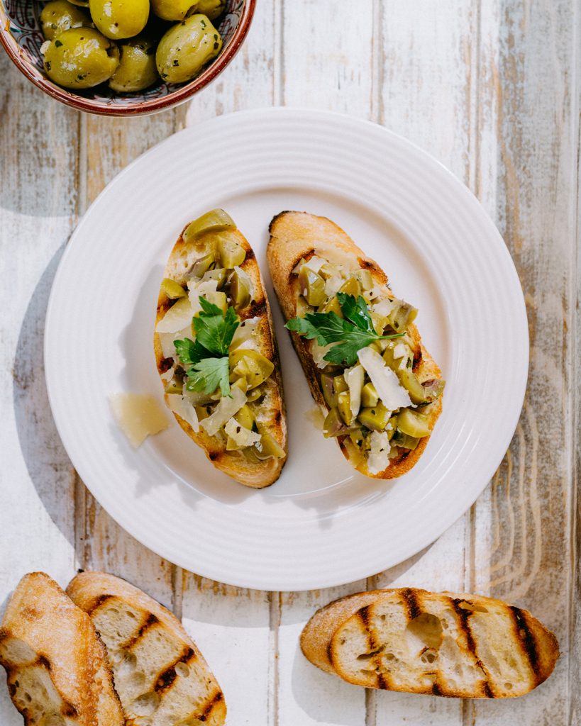 Drei Bruschetta-Variationen mit erlesenen Zutaten und Brot von Morgengold auf den Teller: Bruschetta con Olive